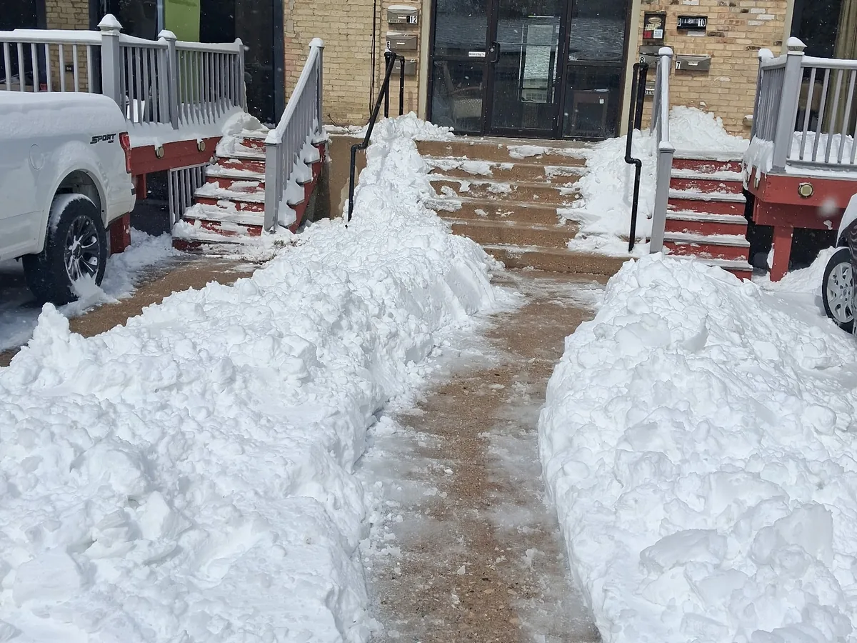 Walkway shoveled to bare pavement between snow piles