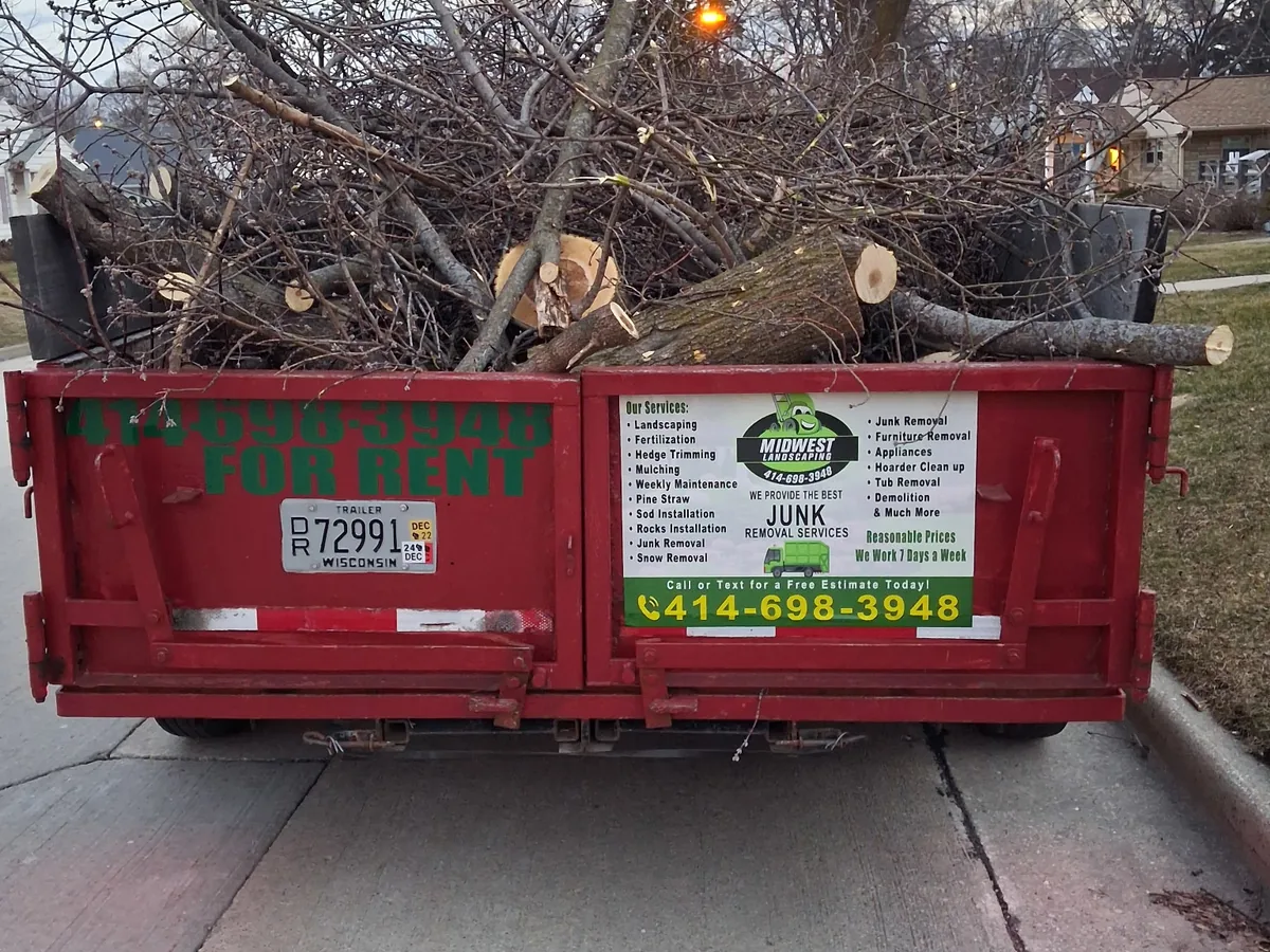 Dump trailer loaded with cut tree limbs and logs